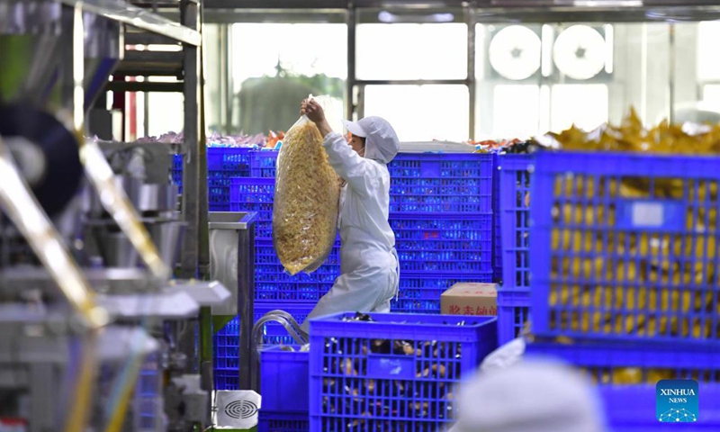 A worker carries ingredients of Luosifen rice noodles at a food-processing company in Liuzhou, south China's Guangxi Zhuang Autonomous Region, Nov. 23, 2021.Photo:Xinhua