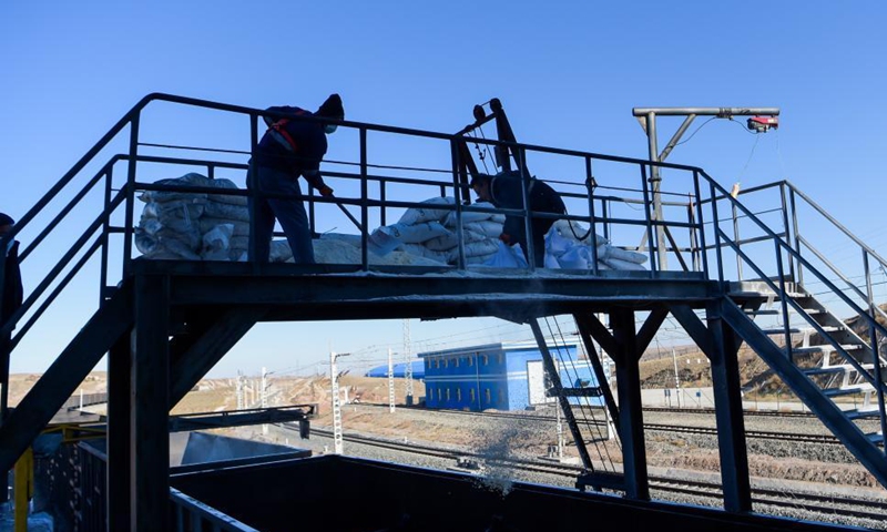 Staff members spread frost-proof powder into a train carriage before loading at a loading station of a coal mine in Erdos, north China's Inner Mongolia Autonomous Region, Nov. 23, 2021.Photo:Xinhua