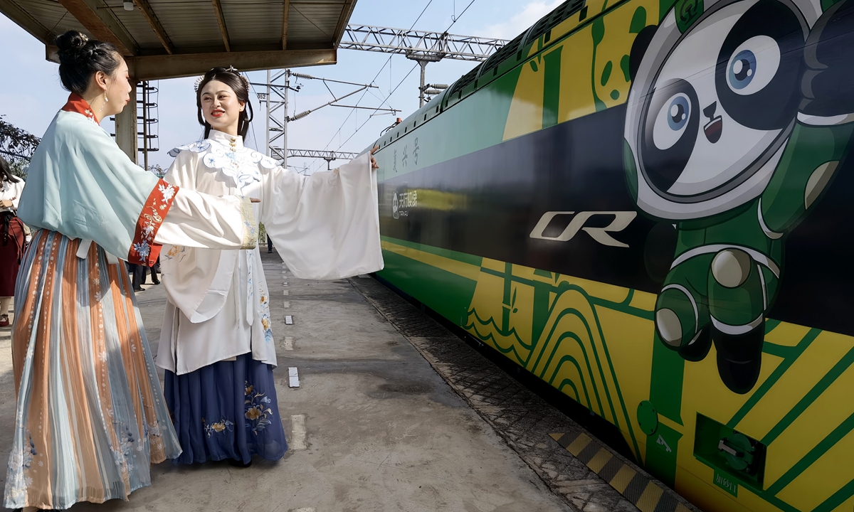 Girls wearing traditional Chinese garments known as hanfu stand by a train painted with cultural elements such as pandas in Suining, Southwest China's Sichuan Province on November 25, 2021. As of the end of 2020, China's high-speed railway system had 37,900 kilometers of track, compared with 19,800 kilometers at the end of 2015.  Photo: cnsphoto