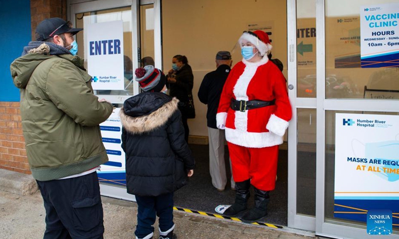 A woman dressed as Santa Claus welcomes a child at the entrance of a vaccination clinic in Toronto, Canada, on Nov 25, 2021. The city of Toronto on Thursday began COVID-19 vaccination for children aged 5 to 11 who have confirmed appointments.Photo:Xinhua