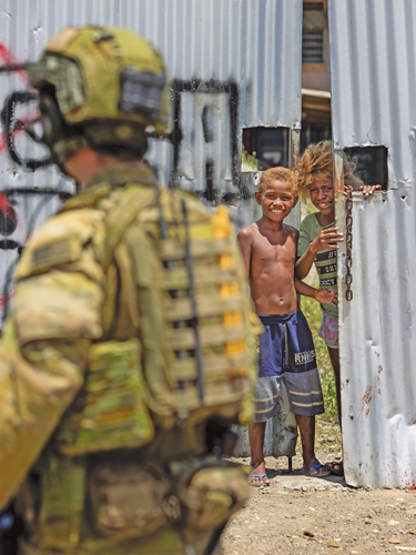 An Australian soldier is watched by young boys during a community engagement patrol through Honiara, Solomon Islands on November 27, 2021.Photo: VCG