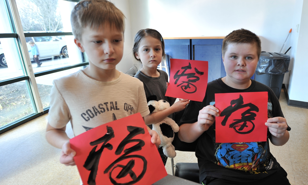 Three children hold the Chinese handwritten character for 