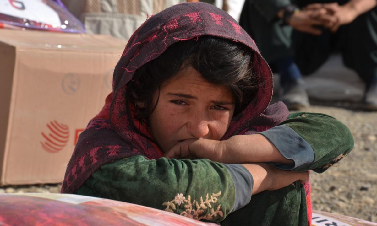 An Afghan girl sits beside relief supplies in Khost province, east Afghanistan, Nov. 9, 2021.  Photo: Xinhua