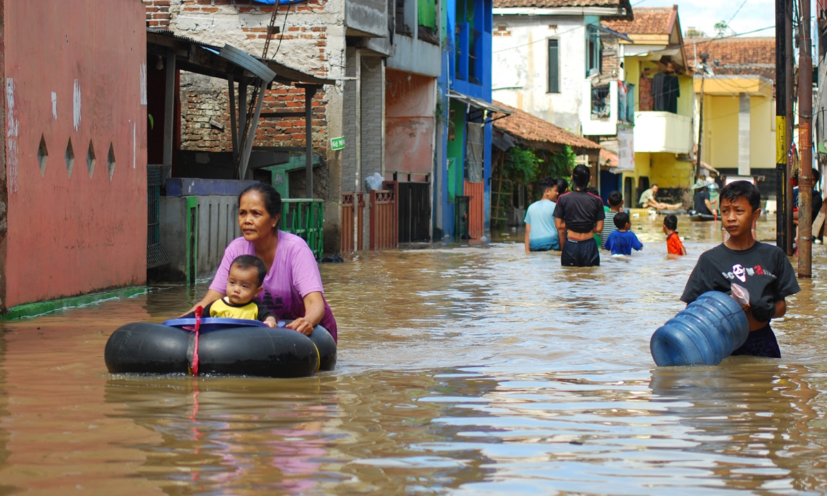 Residents wade through floodwaters following a storm in Bandung, Indonesia on November 28, 2021. Local authorities said that as many as 13 districts and cities in West Java, Indonesia were prone to flash floods during rains at the end of November 2021. Photo: AFP