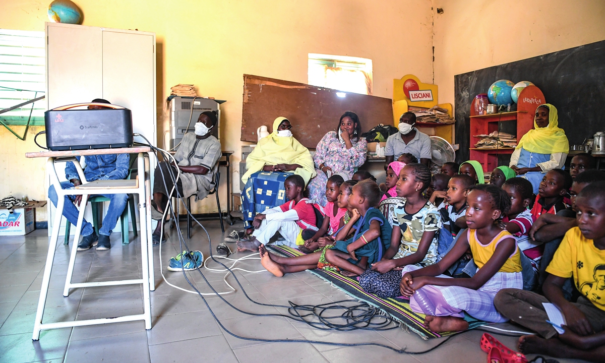 Children watch cartoon through a projector at a village in Dakar, Senegal on November 22, 2021. The China-aided 