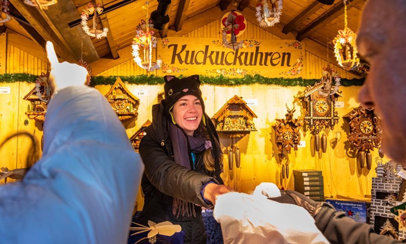 A worker attends to customers at a stand selling cuckoo clocks and ornaments at the Christkindlmarket in Daley Plaza in Chicago, the United States, on Nov. 28, 2021. This year marks the 25th anniversary of the holiday market in Chicago.Photo:Xinhua