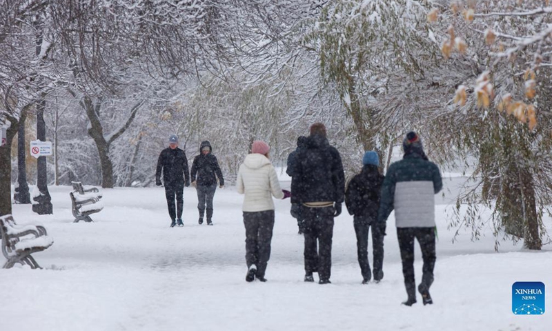 People walk in the snow during a snowy day in a park in Toronto, Ontario, Canada, on Nov. 28, 2021.Photo:Xinhua