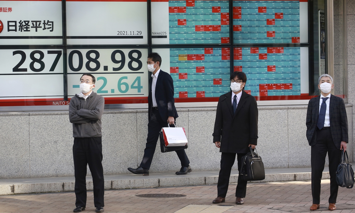 People stand in front of an electronic stock board of a securities firm in Tokyo, November. 29, 2021. Asian stock markets fell further Monday after the omicron variant of the coronavirus was found in more countries and governments imposed travel controls. Photo: AFP