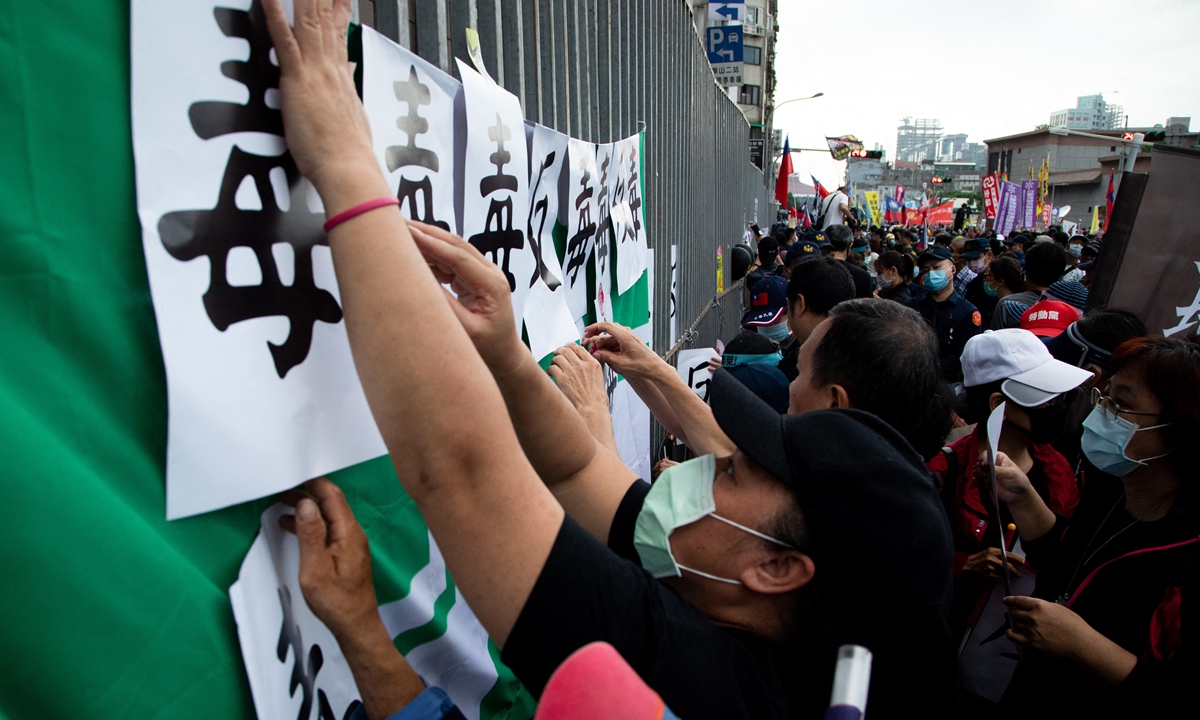 People stick signs that read poison in front of the Democratic Progressive Party's headquarters during a protest in Taipei on November 22, 2020. Photo: AFP