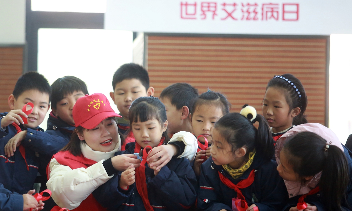 A volunteer in Yangzhou, East China's Jiangsu Province teaches students make badges of red ribbons on November 30, 2021 ahead of World AIDS Day,?which is observed on December 1. China recorded 1.04 million people as having contracted the HIV virus as of 2020. Photo: VCG