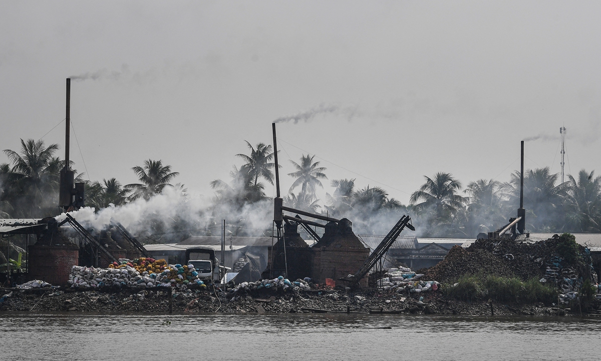 Smoke rises from workshops making charcoal from coconuts along the Mekong river in Ben Tre Province,Vietnam on December 2, 2021. The Vietnamese economy is actively recovering with a rebound in industrial production and retail sales, continued trade surplus and stabilized credit growth from the global COVID-19 pandemic, a World Bank update says. Photo: AFP