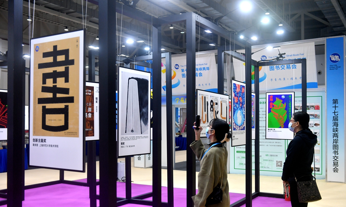 Visitors take pictures of winners of a cross-Straits creative poster competition at the 17th Cross-Strait Book Fair held in Xiamen, East China's Fujian Province on December 2, 2021. More than 60 works were exhibited. 