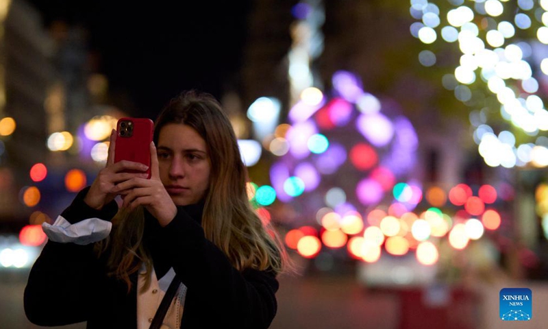 A woman takes photos on a street decorated with festive lights for Christmas in Madrid, capital of Spain, Dec 2, 2021. Photo:Xinhua