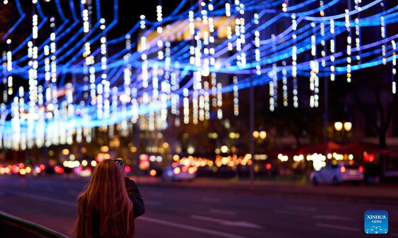 A woman takes photos on a street decorated with festive lights for Christmas in Madrid, capital of Spain, Dec 2, 2021. Photo:Xinhua