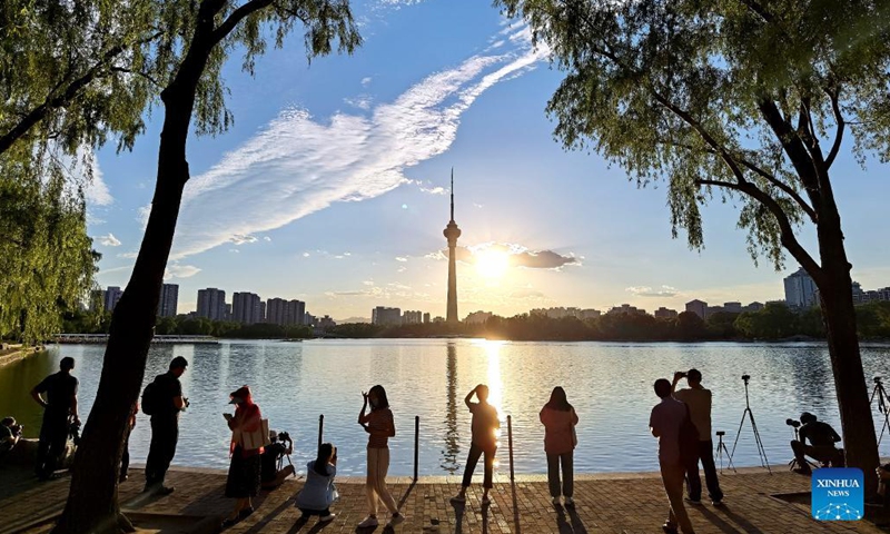 Photo taken with a mobile phone shows people watching sunset in Yuyuantan Park in Beijing, capital of China, June. 17, 2021. Photo:Xinhua