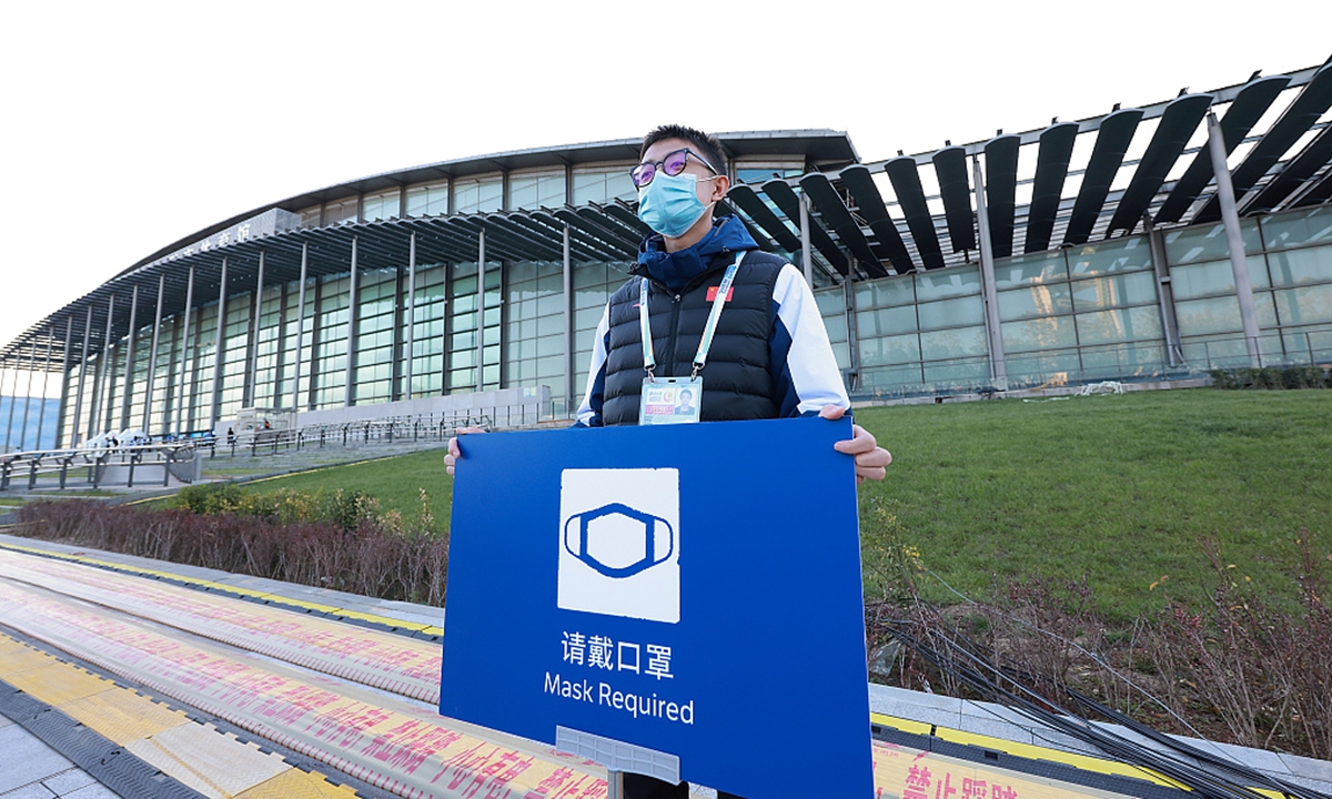 A volunteer wearing a protective mask holds up a sign during a ice hockey test event match, held in preparation of the upcoming Beijing 2022 Winter Olympic Games, at the National Indoor Stadium on November 12, 2021 in Beijing, China. Photo: VCG