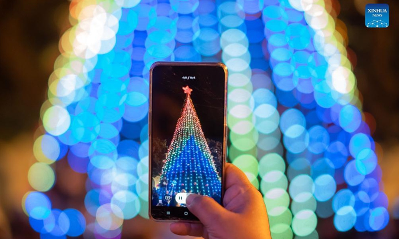 A visitor uses a mobile phone to take photos during the lighting ceremony of the main Christmas tree at the Manger Square in the West Bank city of Bethlehem, on Dec. 4, 2021.Photo:Xinhua