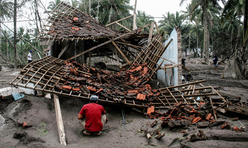 A resident squats in front of a damaged house after the eruption of Mount Semeru in Sumber Wuluh village in Lumajang district, East Java, Indonesia, Dec. 6, 2021.(Photo: Xinhua)