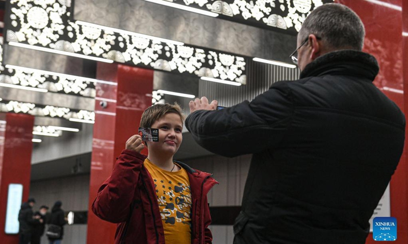 A child holding a metro ticket with a view of Michurinsky Prospekt station printed on it poses for a photo in Moscow, Russia, Dec. 7, 2021. A new section of the Moscow Metro, part of which was built by China Railway Construction Corporation Limited (CRCC) was launched on Tuesday.(Xinhua)