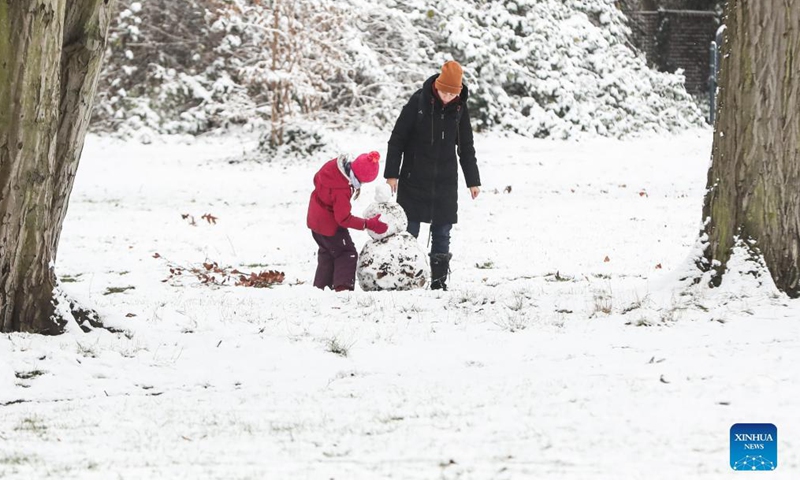 A woman and a child build a snowman at a park in Berlin, capital of Germany, Dec. 9, 2021.Photo:Xinhua