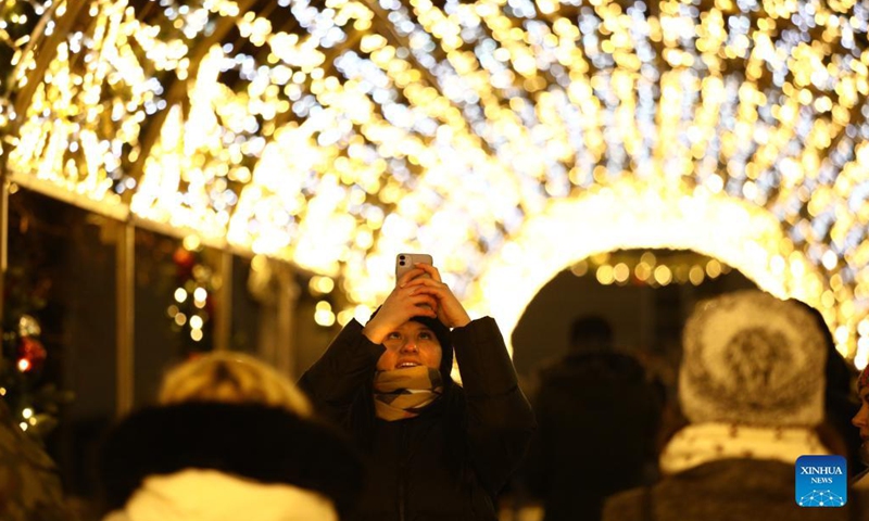 A woman takes a photo of light decorations in Warsaw, Poland, Dec. 7, 2021. Every year the Old Town in the city is decorated with thousands of objects in different colors of lights for the Christmas season.Photo:Xinhua