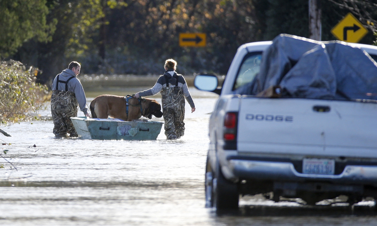 A man and a woman ferry a dog down a flooded Sterling Road in Sedro-Woolley, Washington, the US on November 17, 2021. Photo: AFP