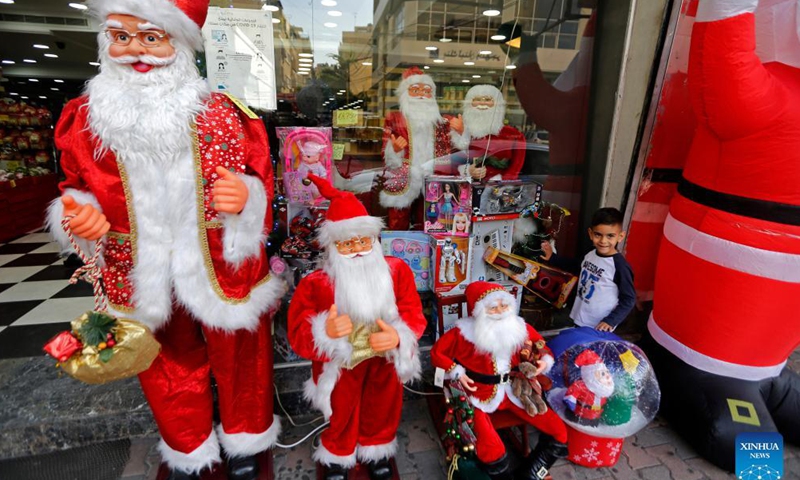 A boy stands in front of a store selling Christmas decorations in Beirut, Lebanon, on Dec. 11, 2021.Photo:Xinhua