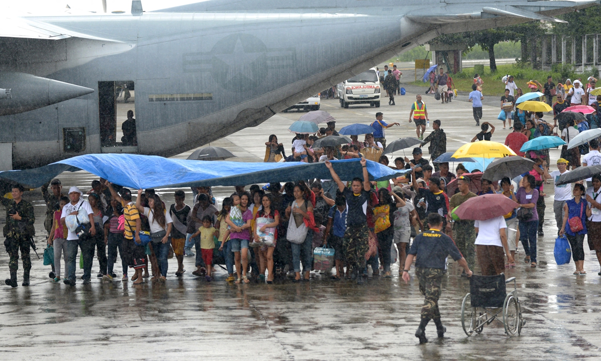 Survivors of Typhoon Haiyan walk on the tarmac after disembarking from a Philippine Air Force military cargo plane in Manila, the Philippines on November 26, 2013. Photo: AFP
