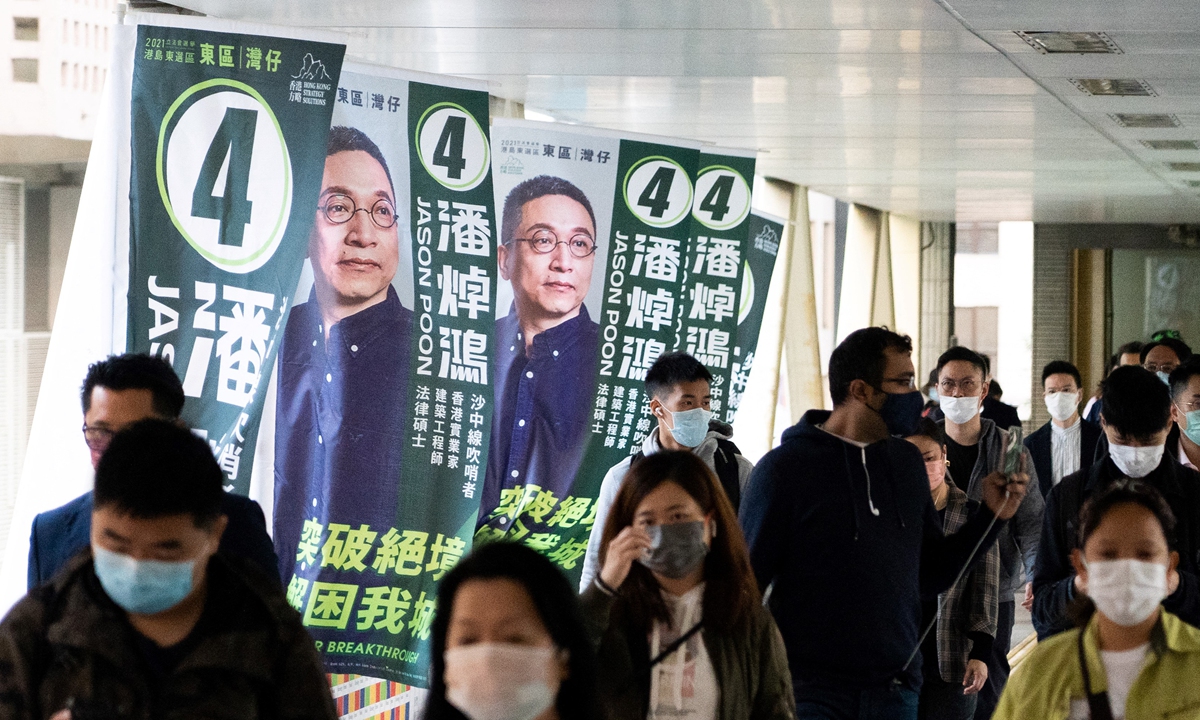 People walk past campaign banners for Hong Kong Legislative Council candidate Jason Poon ahead of the election to be held on December 19. Photo: AFP