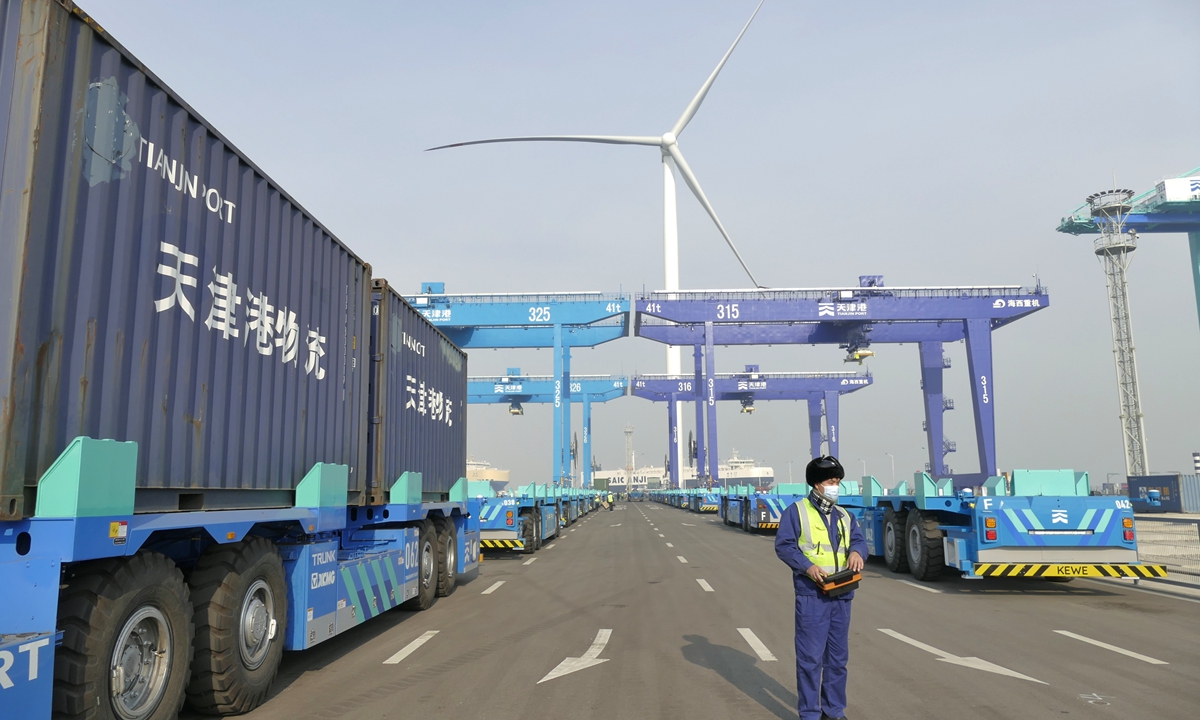 A worker directs a robot to start a wind power plant at an intelligent container port in North China's Tianjin Municipality on December 15, 2021. The plant has successfully connected to the grid, making Tianjin port the world's first zero-carbon port to use a smart green energy system. Photo: cnsphotos