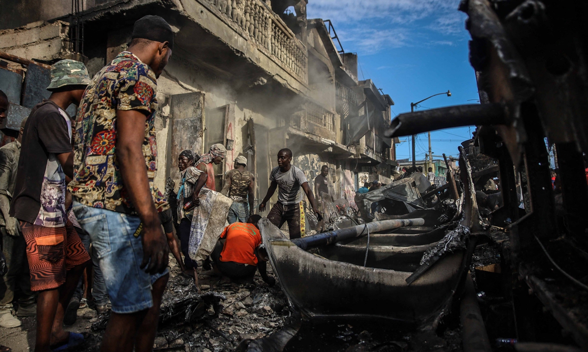 Men pick up aluminum pieces at the site where a tanker truck exploded in Cap-Haitien, Haiti on December 14, 2021. Photo: AFP