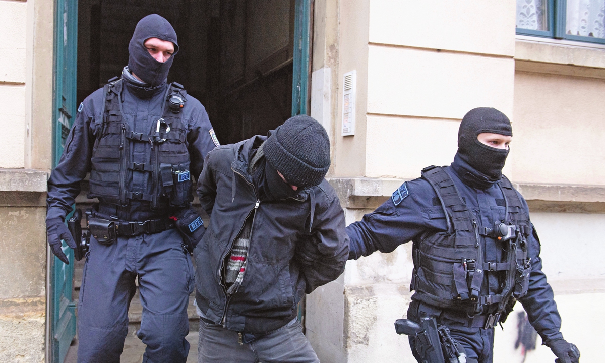 Police lead a suspect out of a building in a raid in Germany on December 15, 2021, after threats against Saxony's Prime Minister Kretschmer. Photo: VCG