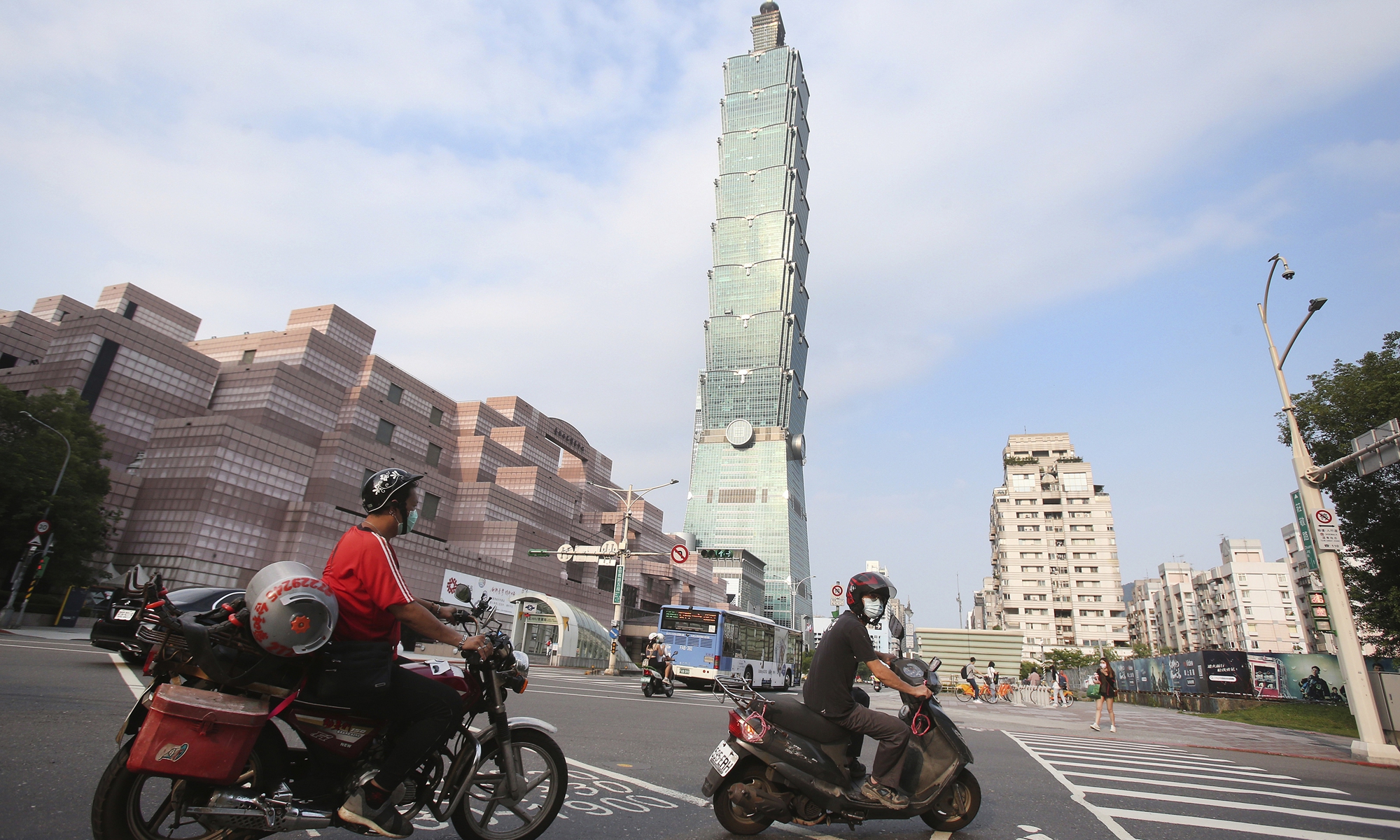 People wear face masks to protect against the spread of the coronavirus as they ride past the Taipei 101 building after the COVID-19 alert was raised to level 3 in Taipei, the island of Taiwan on May 15, 2021. Photo: VCG
