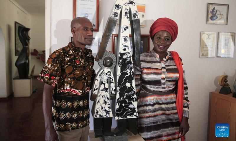 David Ngwerume, one of Zimbabwe's most decorated artists, who is known for his pandemic-inspired art, shows his artwork to Zimbabwe's Acting Minister of Youth, Sport, Arts and Recreation Sekai Nzenza at his studio in Harare, Zimbabwe, Dec. 9, 2021. Two of Zimbabwe's renowned stone sculptors will showcase their talent at the 9th Beijing International Art Biennale which will start next month.(Photo: Xinhua)