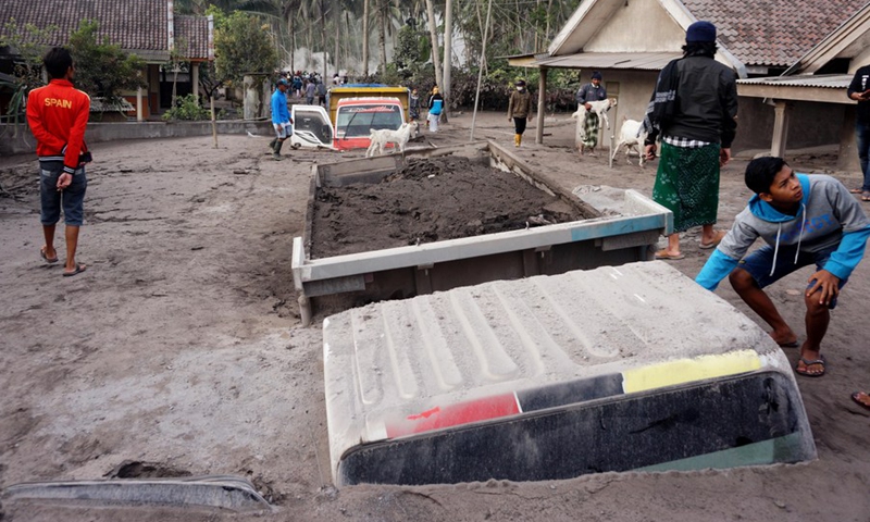 People walk near trucks buried in volcanic ashes after Mount Semeru eruption in Lumajang, East Java, Indonesia, Dec. 5, 2021.(Photo: Xinhua)