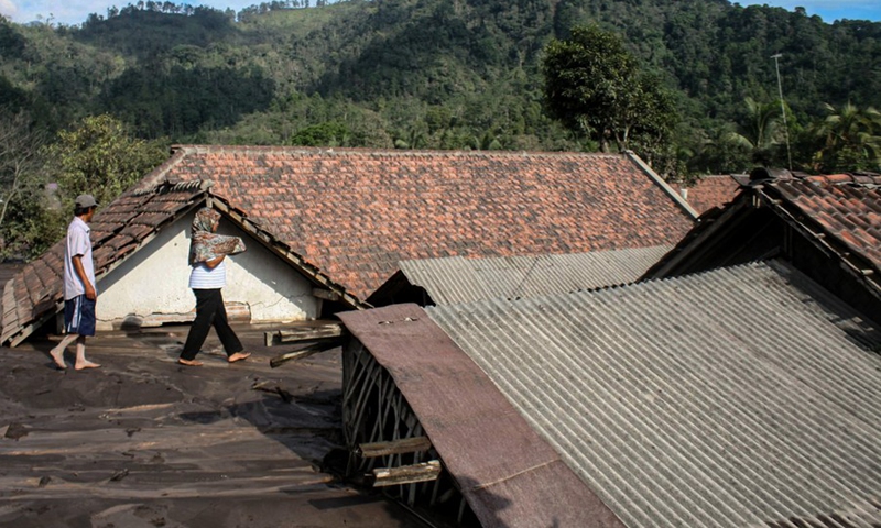 People walk by houses buried in volcanic ash after Mount Semeru eruption in Lumajang, East Java, Indonesia, Dec. 9, 2021. (Photo: Xinhua)