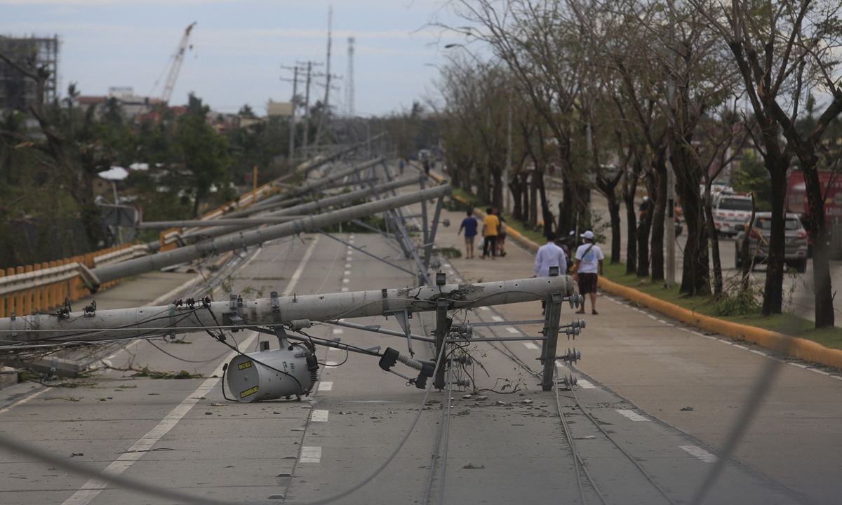 Residents walk past downed electric pylons in Talisay town, Cebu province on December 17, a day after Super Typhoon Rai pummelled the southern and central regions of the Philippines. Photo: AFP