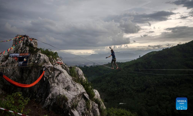 A participant balances on a rope during Bandung Highline Festival 2021 in Bandung, West Java, Indonesia. Dec. 18, 2021. (Photo by Septianjar/Xinhua)  