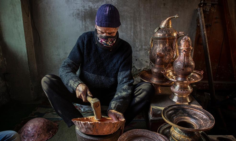 A coppersmith makes a copper pot at a workshop in Srinagar city, the summer capital of Indian-controlled Kashmir, Dec. 18, 2021.Photo:Xinhua