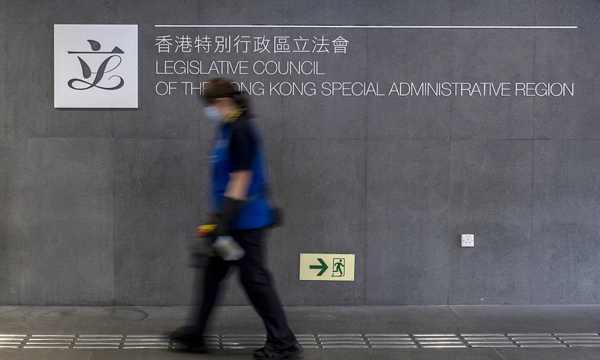 A cleaner walks past signage at the Legislative Council building in Hong Kong, China. File Photo: VCG