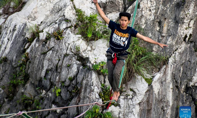A participant balances on a rope during Bandung Highline Festival 2021 in Bandung, West Java, Indonesia. Dec. 18, 2021. (Photo by Septianjar/Xinhua)  