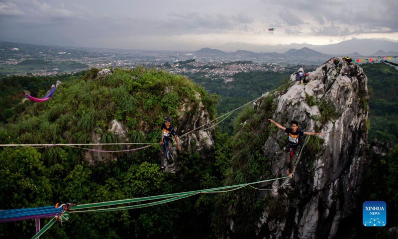 A participant balances on a rope during Bandung Highline Festival 2021 in Bandung, West Java, Indonesia. Dec. 18, 2021. (Photo by Septianjar/Xinhua)  