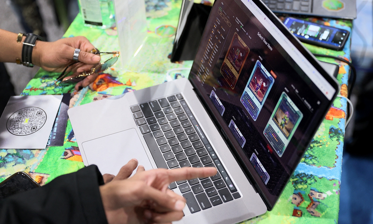Attendees look at game DeFi Kingdoms on a laptop during the DCentral Miami Conference.People gather at the WAX booth during the DCentral Miami Conference at the Miami Airport Convention Center on December 1, 2021 in Miami, the US. 
Photos: AFP 