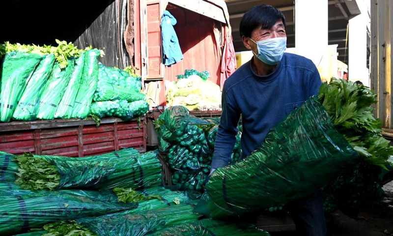 A staff member carries vegetable at a logistics center in Xi'an, northwest China's Shaanxi Province, Dec. 19, 2021.Photo:Xinhua