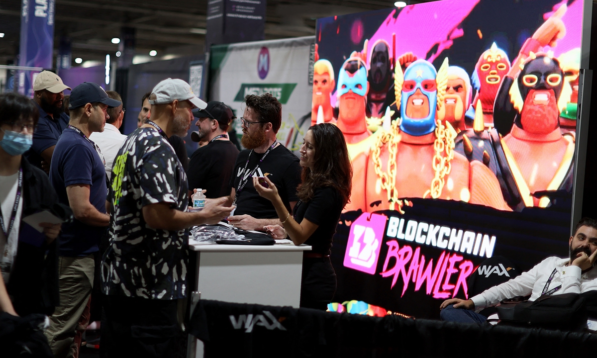 Attendees look at game DeFi Kingdoms on a laptop during the DCentral Miami Conference.People gather at the WAX booth during the DCentral Miami Conference at the Miami Airport Convention Center on December 1, 2021 in Miami, the US. 
Photos: AFP 