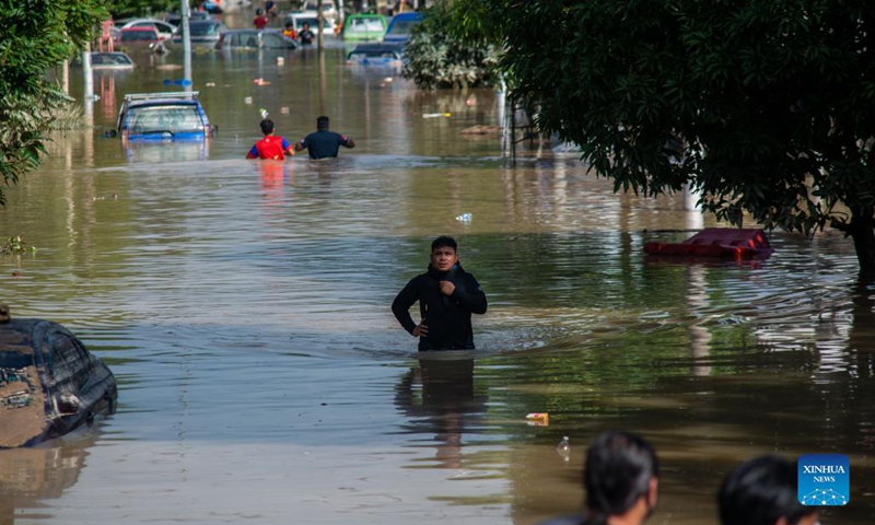 Flood victims wade through a flooded road in Shah Alam, Selangor, Malaysia, Dec. 20, 2021. Eight people have been reported dead due to severe flooding in Malaysia as of Monday, authorities in Selangor state said.(Photo: Xinhua)