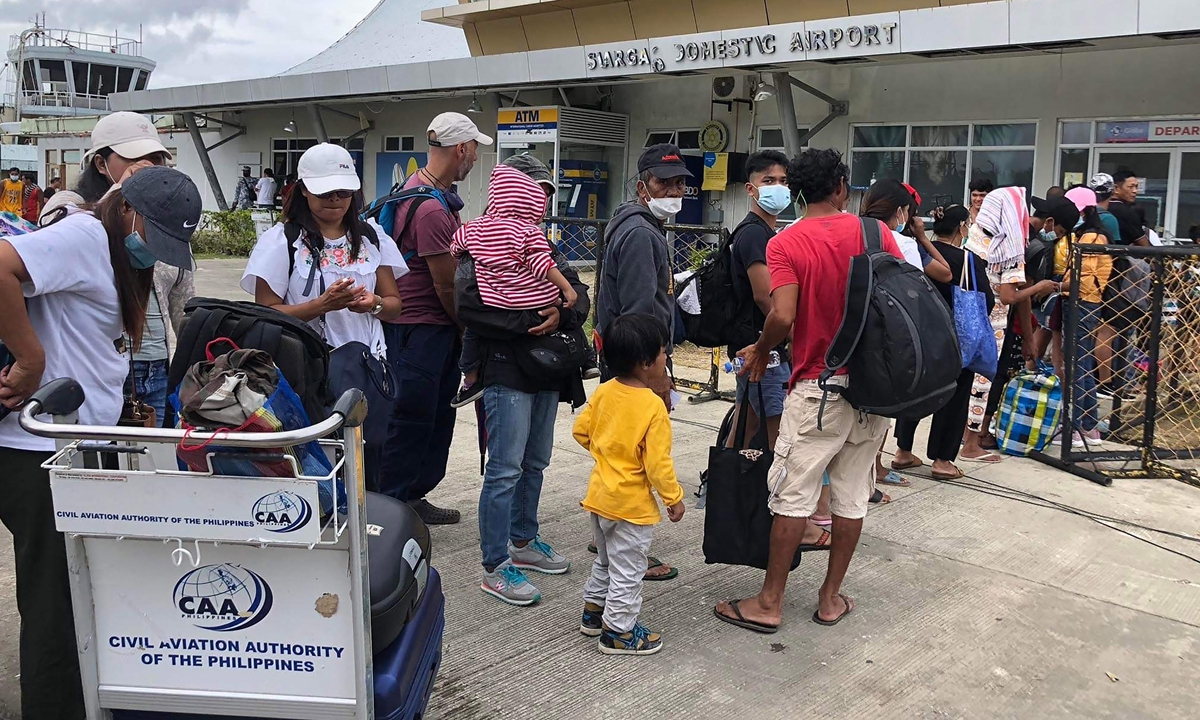 People queue up to board a humanitarian flight out of Siargao airport in Del Carmen, Siargao island, the Philippines on December 21, 2021, days after Super Typhoon Rai hit the island. Photo: AFP