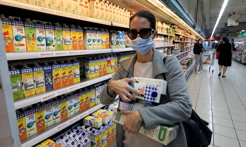 Photo taken on Dec. 21 shows a customer buying several cartons of milk, which are printed with Hebrew words, at a supermarket in central Israeli city of Modiin on Dec. 21, 2021.(Photo: Xinhua)