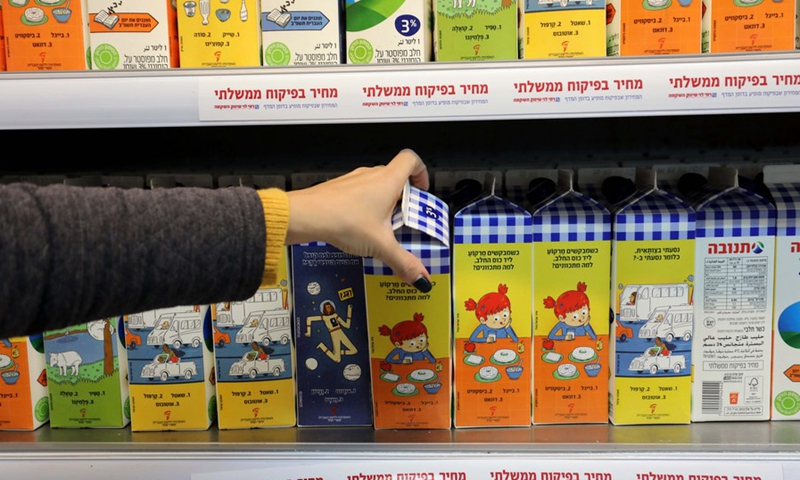 A customer selects a carton of milk printed with Hebrew words at a supermarket in central Israeli city of Modiin.(Photo: Xinhua)