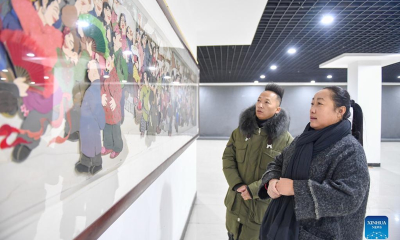Li Baofeng (R) looks at paper cutting works in Changchun, northeast China's Jilin Province, Dec. 17, 2021. Li Baofeng, 56, is a paper cutting artist in Jilin. Combining traditional paper cutting technique with features of various painting forms like the Chinese painting, oil painting and printmaking, Li creates her own art style. Her works are rich in color and strong in three-dimensional sense. Most of her creations focus on the Chinese classical literature, folk customs and landscapes.(Photo: Xinhua)